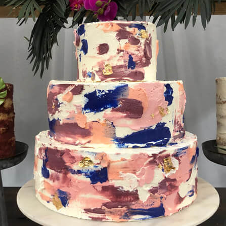 Hand-painted colorful buttercream wedding cake with gold leaf