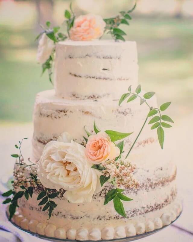 Rustic naked wedding cake decorated with fresh flowers