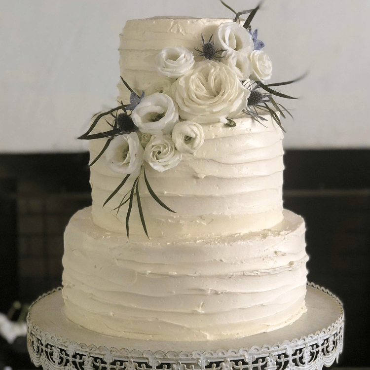 3 tier wedding cake with ribbon texture and white floral arrangement