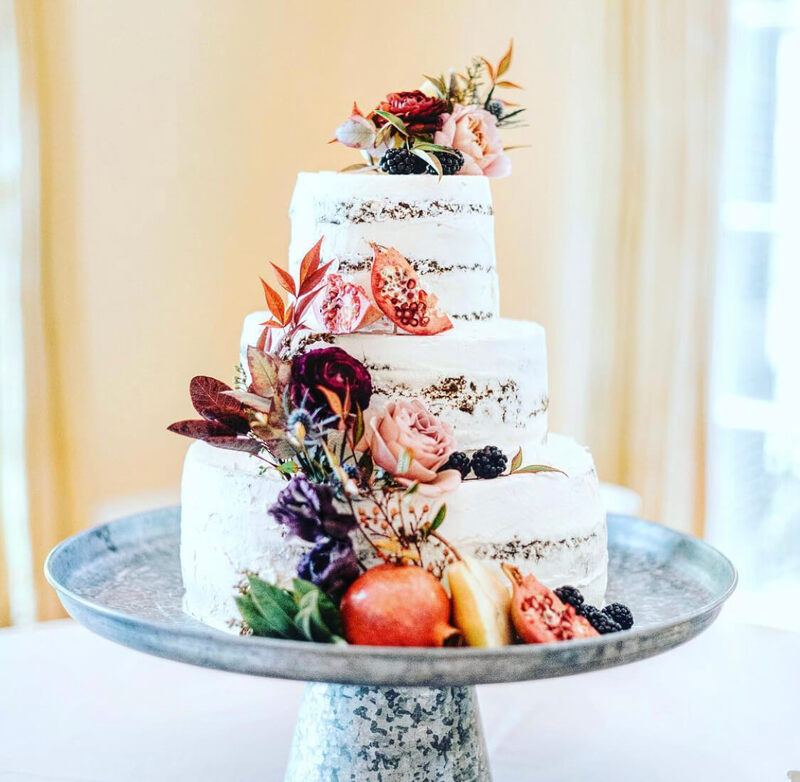 Naked wedding cake covered with fall flowers and figs
