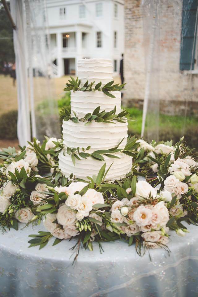 Simple, elegant wedding cake with rippled icing and greenery