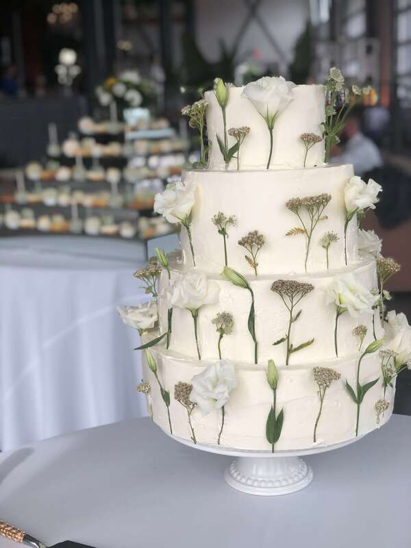 4 tier wedding cake covered in fresh cut white flowers