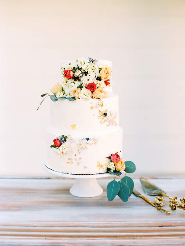 3 tier wedding cake covered in hand-painted flowers and fresh flowers